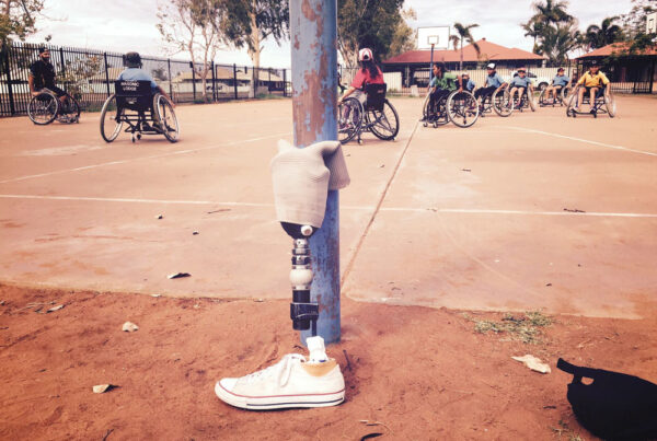 A prothetic leg leaning against a pole at the edge of a wheelchair basketball game in remote Australia